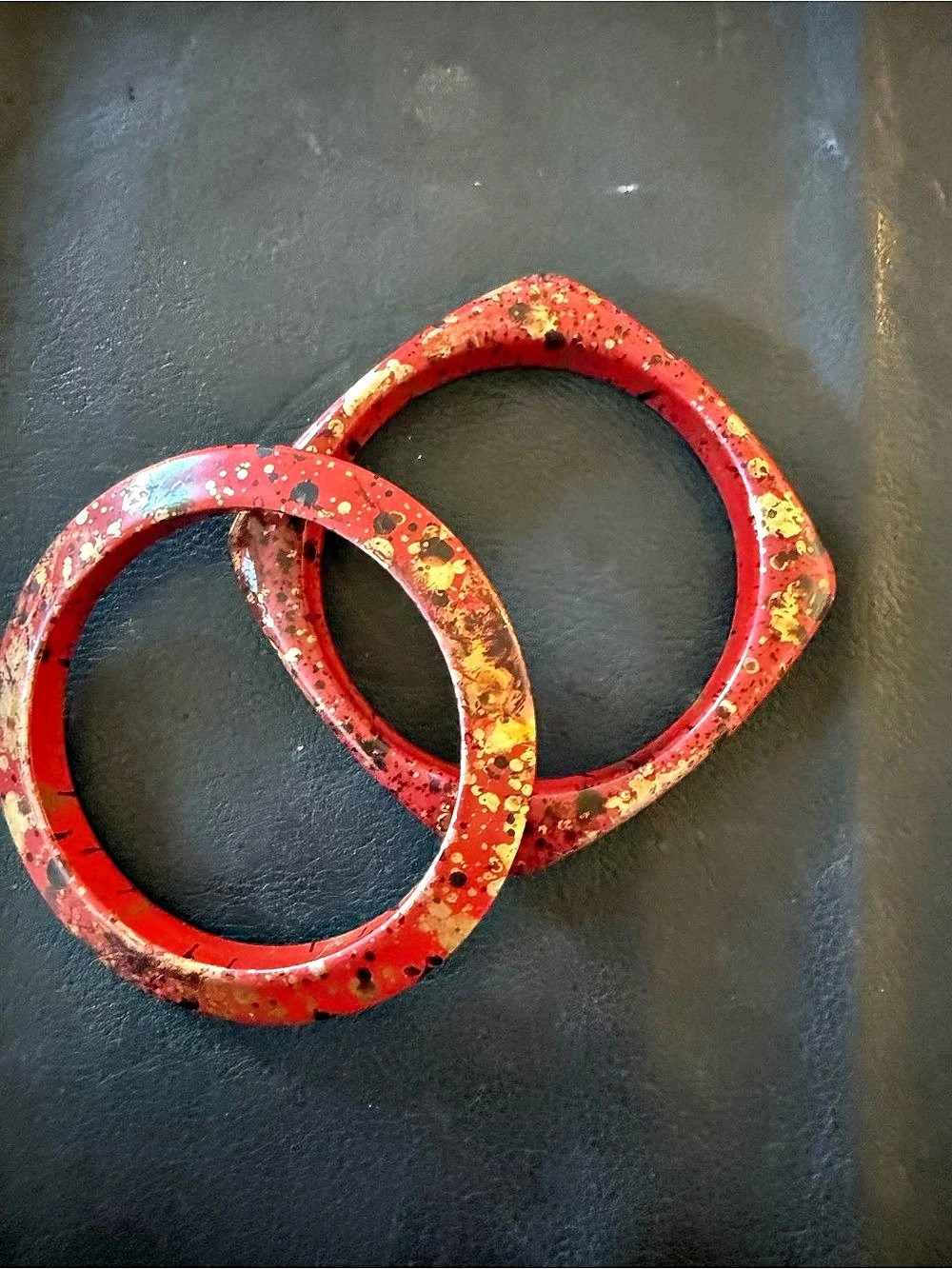 pair of red and gold splatter-patterned resin and lucite bangles, including a ro